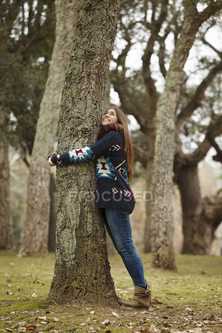 Jovem mulher abraçando árvore na floresta — Fotografia de Stock