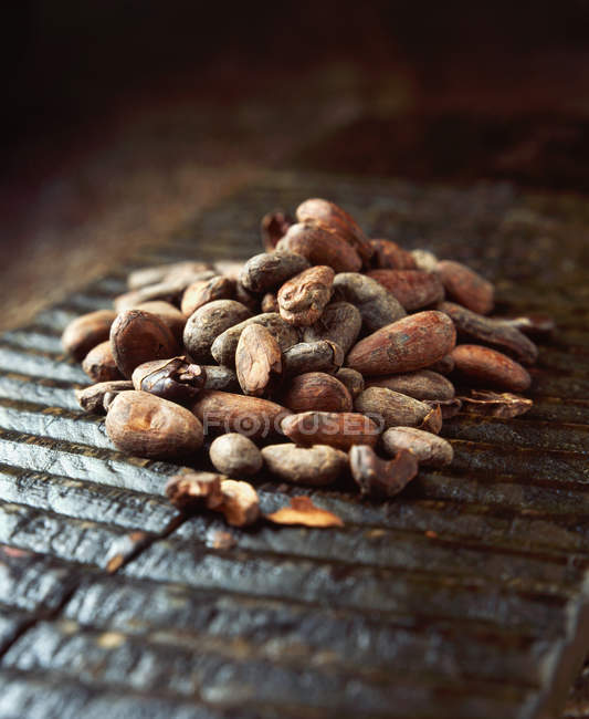 Raw cocoa beans on ridged wooden board, close up — Stock Photo