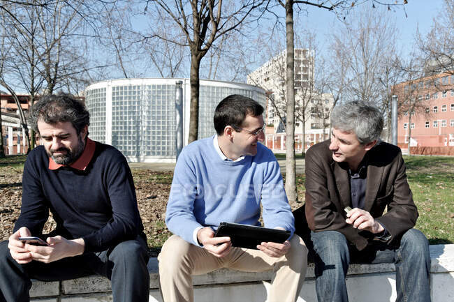 Зрелые бизнесмены используют цифровой планшет и мобильный телефон снаружи — стоковое фото
