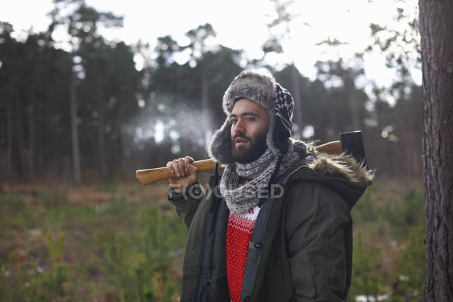 Молодий чоловік носить сокиру над плечем у лісі — стокове фото