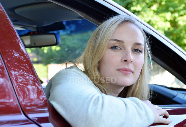Portrait of young woman looking through car window — Stock Photo
