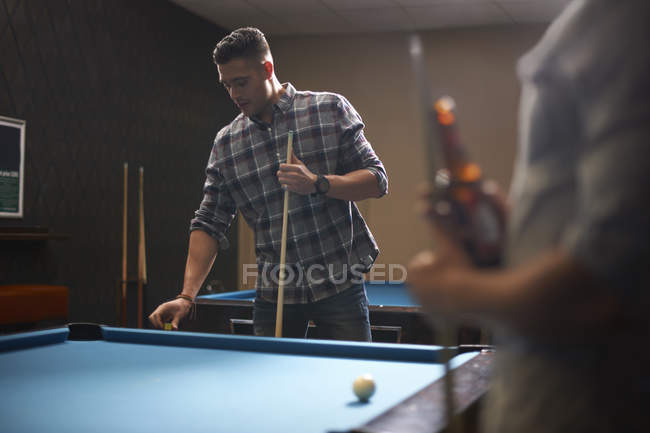 Homem se preparando para jogar bilhar, amigo com cerveja em primeiro plano — Fotografia de Stock