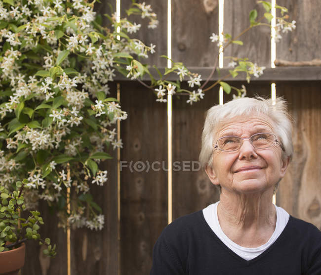 Портрет улыбающейся пожилой женщины в саду, смотрящей вверх — стоковое фото