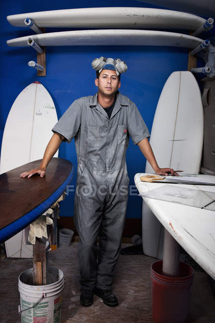 Retrato de hombre adulto medio y tablas de surf en taller - foto de stock