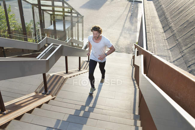 Чоловік біжить міськими сходами — стокове фото