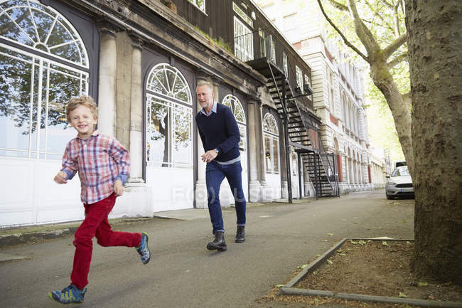 Caucasian father and son running on street, London, UK — Stock Photo