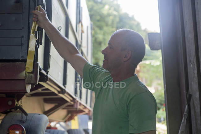 Male farmer unlocking trailer in barn — Stock Photo