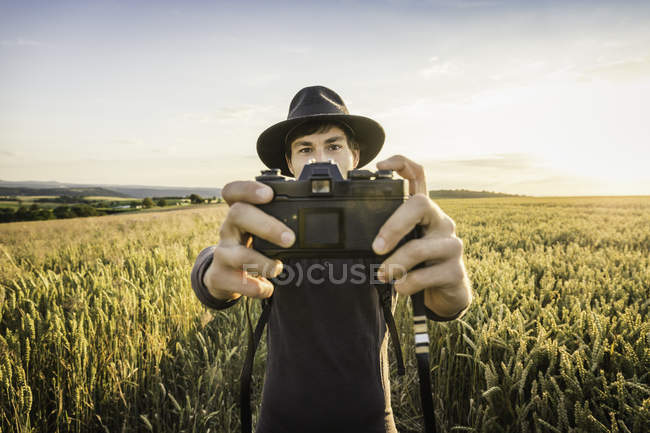 Man taking selfie with SLR camera in field — Stock Photo