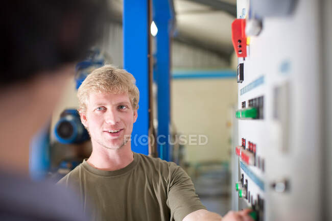 Hombre en el panel de control en la planta de procesamiento de aceitunas - foto de stock