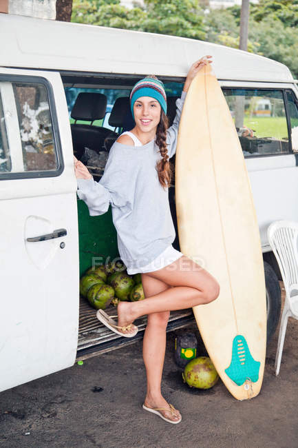 Young woman with surfboard by campervan — Stock Photo