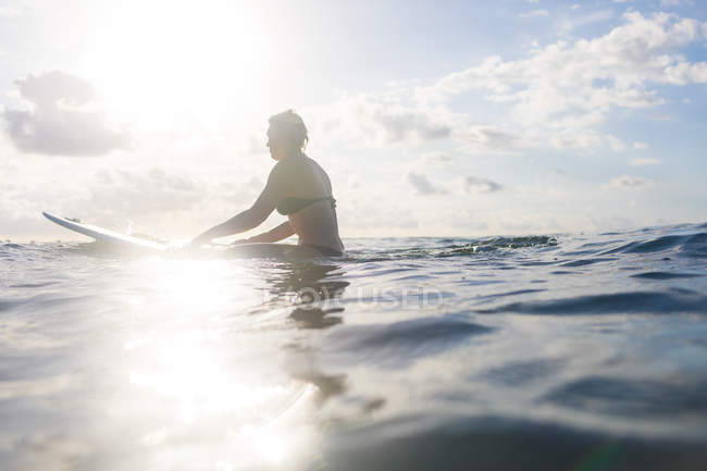 Woman straddling surfboard in sunlit sea, Nosara, Guanacaste Province, Costa Rica — Stock Photo