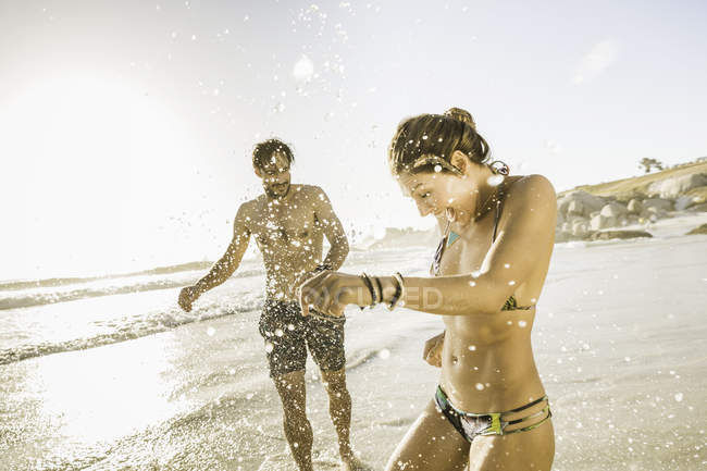 Metà coppia adulta in bikini e pantaloncini spruzzi sulla spiaggia, Città del Capo, Sud Africa — Foto stock