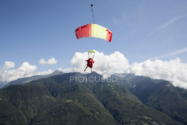 Скайдайвер под парашютом, свободно летающий в голубом небе, Локарно, Тессин, Швейцария — стоковое фото
