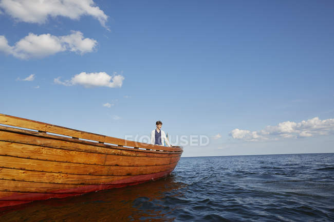 Menino adolescente no barco olhando para longe no oceano azul — Fotografia de Stock