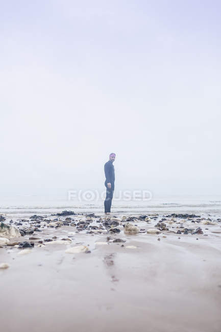 Portrait d'un homme mature portant une combinaison, debout sur la plage — Photo de stock