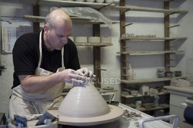 Männlicher Töpfer formt Tontopf auf Töpferscheibe in Werkstatt — Stockfoto