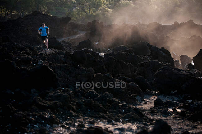 Uomo che corre su una spiaggia rocciosa — Foto stock
