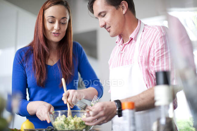 Cocina en pareja, mezclando ingredientes en un tazón - foto de stock