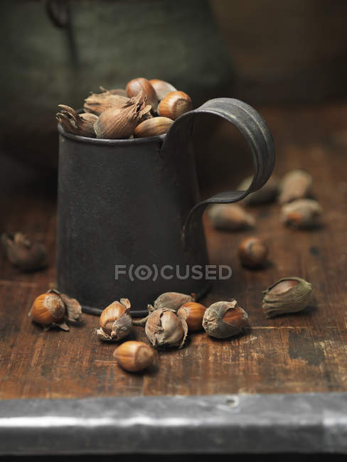 Cobnuts in vintage metal tankard on wooden table — Stock Photo