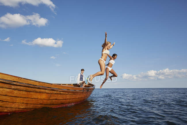 Жінки стрибають з човна в блакитному океані — стокове фото