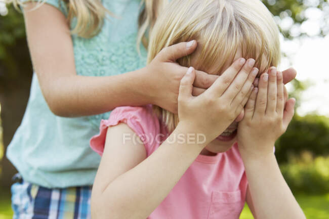 Abgeschnittene Aufnahme eines Mädchens mit Händen, die die Augen eines Freundes im Garten verdecken — Stockfoto