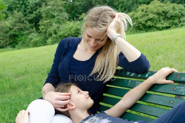 Madre e figlia si rilassano sulla panchina del parco — Foto stock