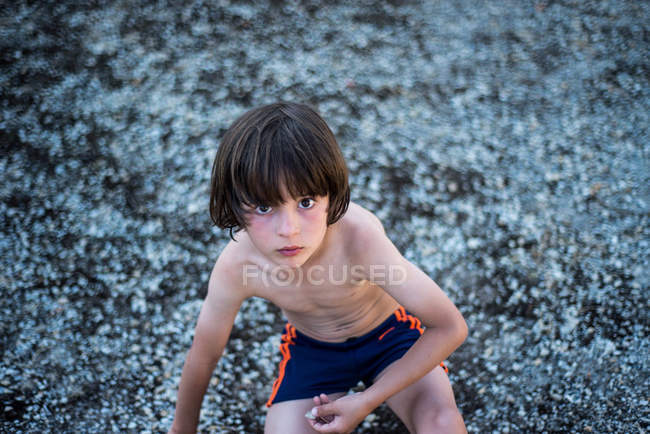 Ritratto di ragazzo dal petto nudo che indossa pantaloncini guardando la macchina fotografica — Foto stock