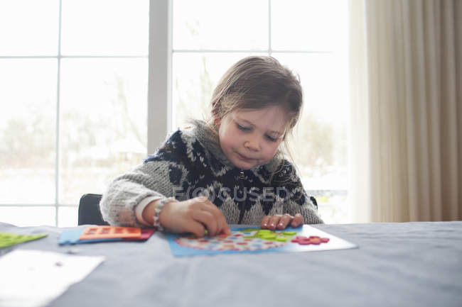 Jovem sentada à mesa concentrando-se no jogo — Fotografia de Stock