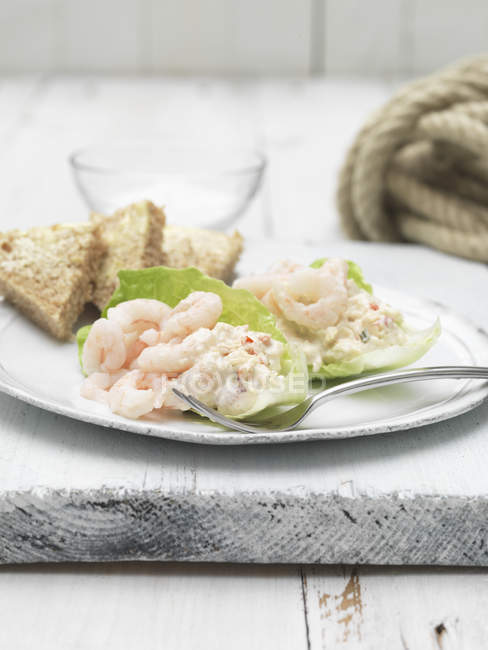 Prawns with lettuce and slices of bread on plate — Stock Photo
