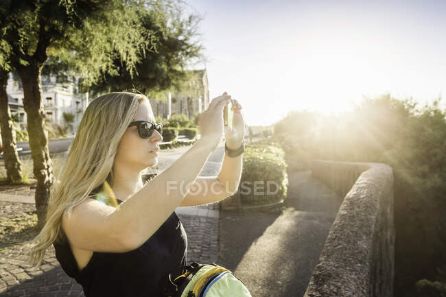 Mujer joven fotografiando con smartphone, Biarritz, Francia - foto de stock