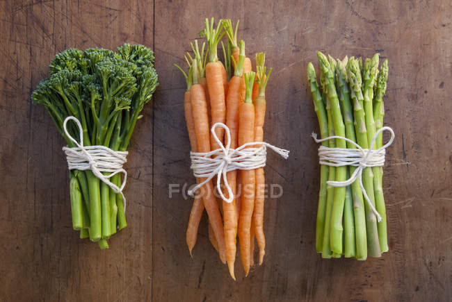 Racimos de zanahorias, brócoli y espárragos atados con cuerdas - foto de stock