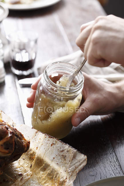 Manos masculinas usando tenedor en frasco de salsa de manzana - foto de stock