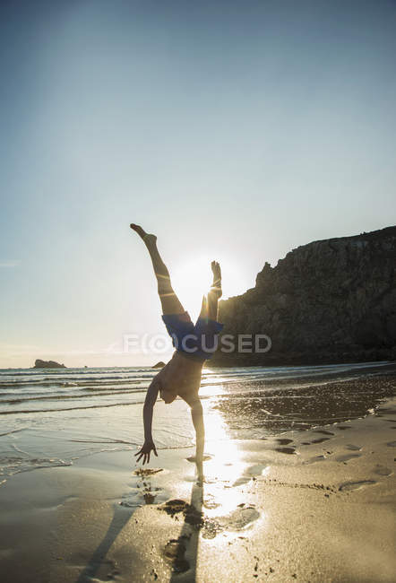 Teenage boy doing handstand at beach, Camaret-sur-mer, Bretaña, Francia - foto de stock