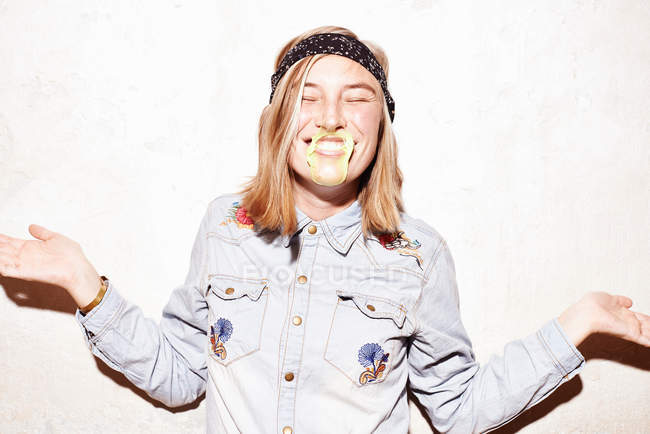 Mujer joven con burbuja de goma de mascar amarilla en la cara - foto de stock