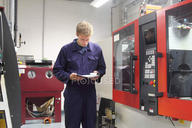 Male engineer checking machinery paperwork in factory — Stock Photo