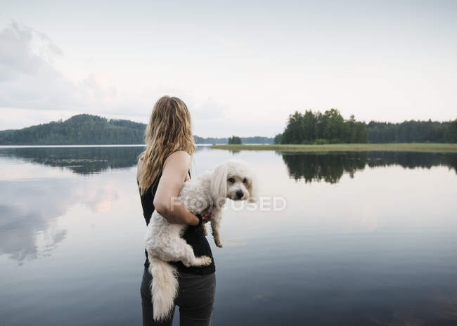 Mulher carregando cotão de tulear cão no lago, Orivesi, Finlândia — Fotografia de Stock