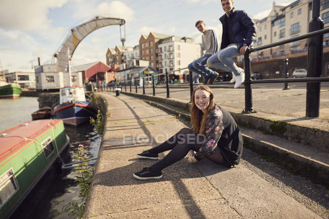 Portrait of three friends sitting beside river, Bristol, UK — Stock Photo