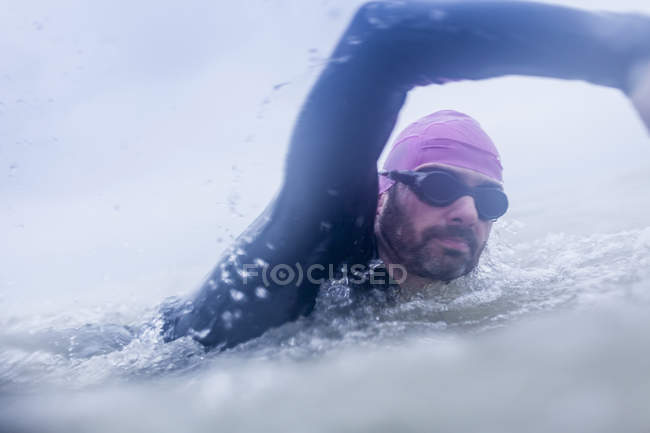 Зрілий чоловік плаває у морі, як у водолазному костюмі та окулярах. — стокове фото