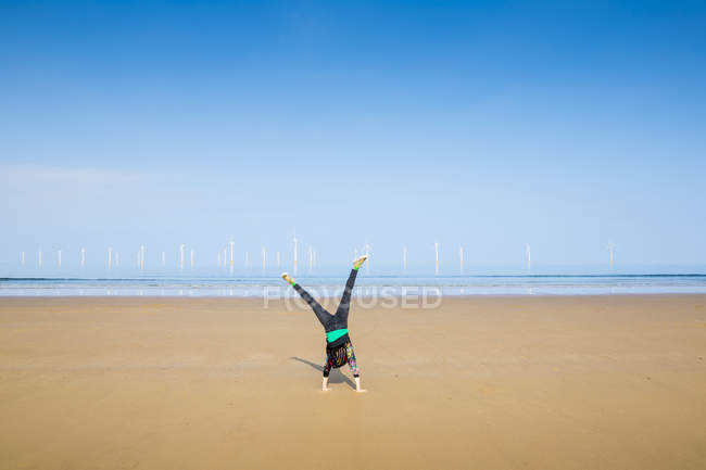 Mature woman doing cartwheel on Redcar beach, North Yorkshire, UK — Stock Photo