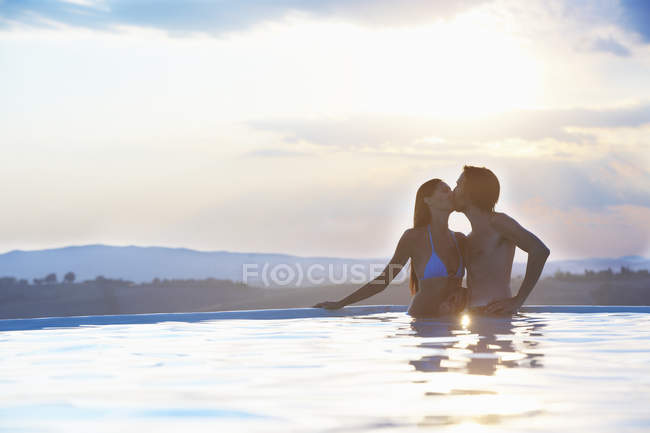 Pareja romántica besándose en piscina al aire libre - foto de stock