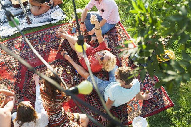 Overhead view of group of friends relaxing on rug at sunset park party — Stock Photo
