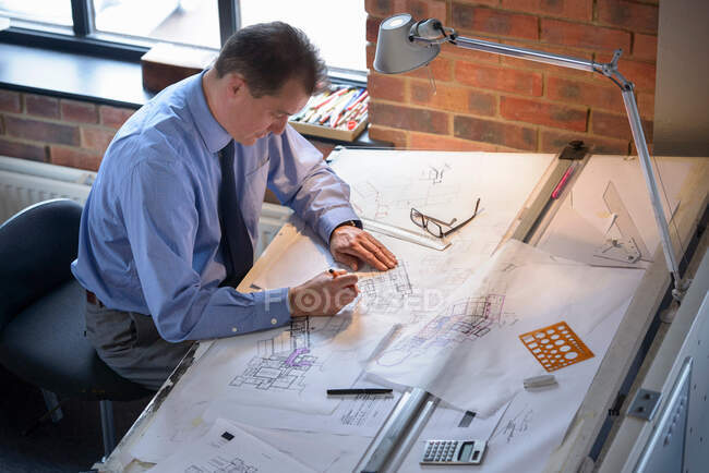 Architect drawing plans at drawing board — Stock Photo