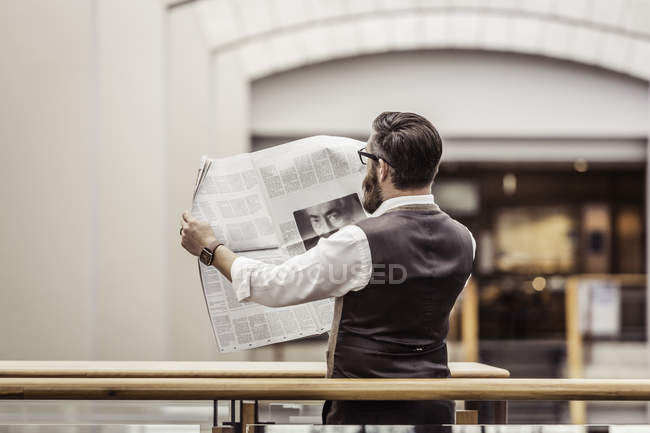 Uomo d'affari che legge giornale sul balcone dell'ufficio — Foto stock
