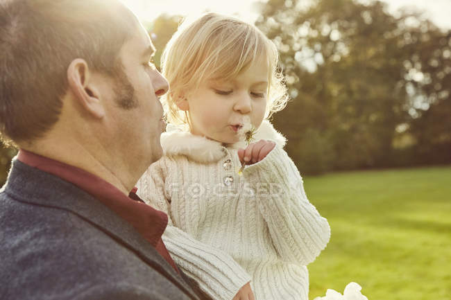 Father and daughter looking at dandelion clock — Stock Photo
