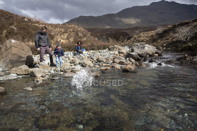 Family throwing stones in pond, Fairy Pools, Isle of Skye, Hebrides, Scotland — Stock Photo