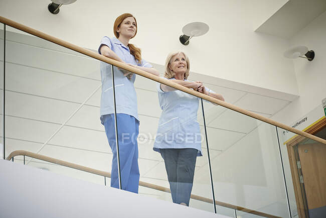 Dos enfermeras esperando en el balcón del atrio del hospital - foto de stock