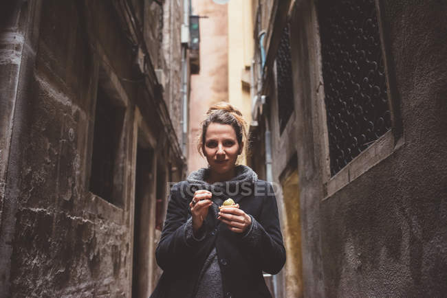 Portrait of young woman eating gelato in dark alley, Venice, Italy — Stock Photo