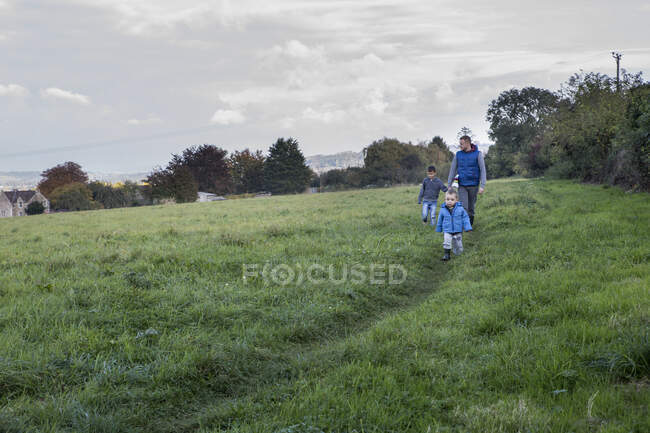 Padre e hijos caminando en el campo - foto de stock