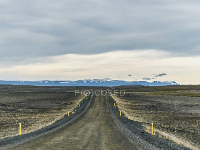 Montanhas distantes e estrada pista de terra — Fotografia de Stock