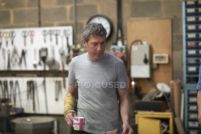 Male caucasian Glassblower in workshop holding mug — Stock Photo